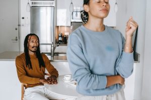 A woman turns her back on her boyfriend, looking frustrated while avoiding talking to him.
