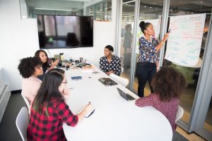 A team of women brainstorms for ideas around a conference table.
