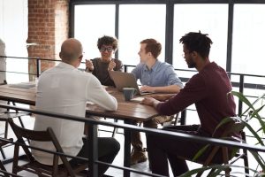 A group of business professionals sitting around a table talking.