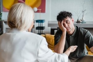 A man puts his hand over his face in frustration as he listens to his girlfriend.