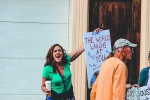 A woman yells and holds up a protest sign at a demonstration.
