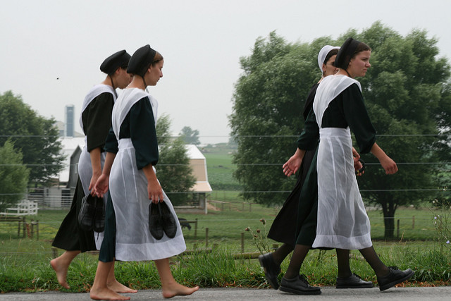 Four Amish women walking along the side of a road