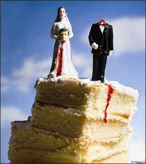 A slice of wedding cake with a groom and wife figurine. The wife figurine is holding the head of the groom in her hands