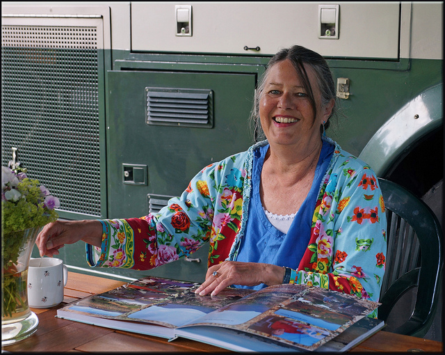 A woman in a colorful shirt looking at a scrapbook
