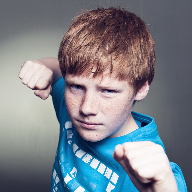 A young boy posing with his fists up towards the camera