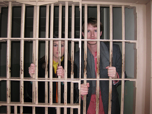 A man and a woman standing behind bars at a jail